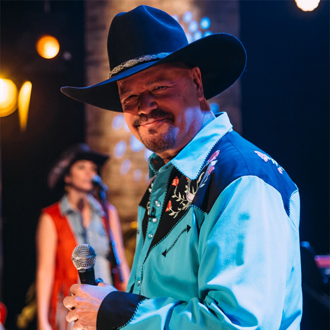 man wearing cowboy hat and blue country shirt holding microphone