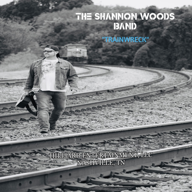 man walking on railroad tracks with guitar